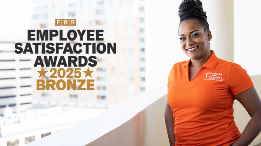 Right at Home caregiver standing next to a Franchise Business Review 2025 Bronze Employee Satisfaction Award badge