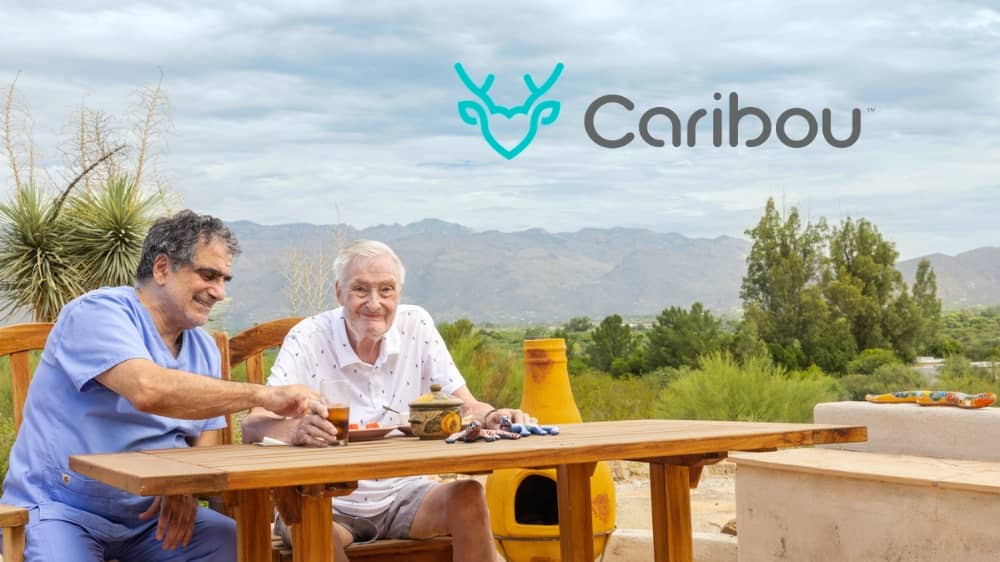 Male Right at Home caregiver playing chess with a senior client at a table. Next to them is a logo that says "Caribou."
