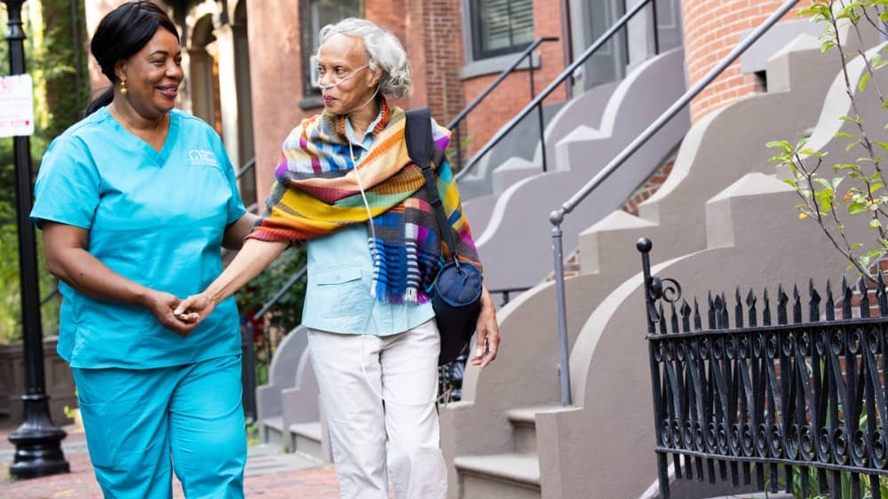 Female Right at Home Caregiver walking down the sidewalk with a senior female client