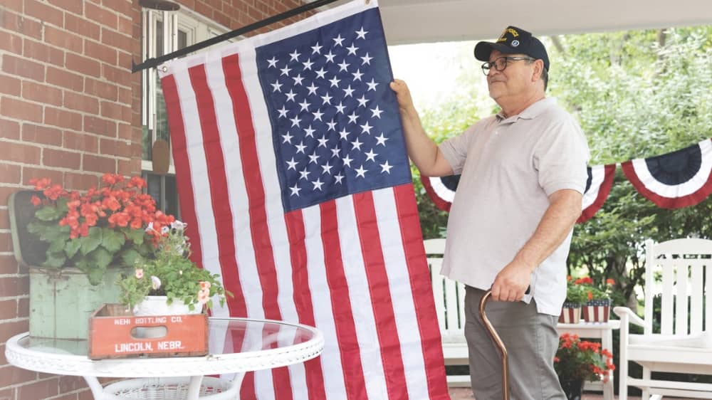 Male veteran standing outside and looking at an American flag