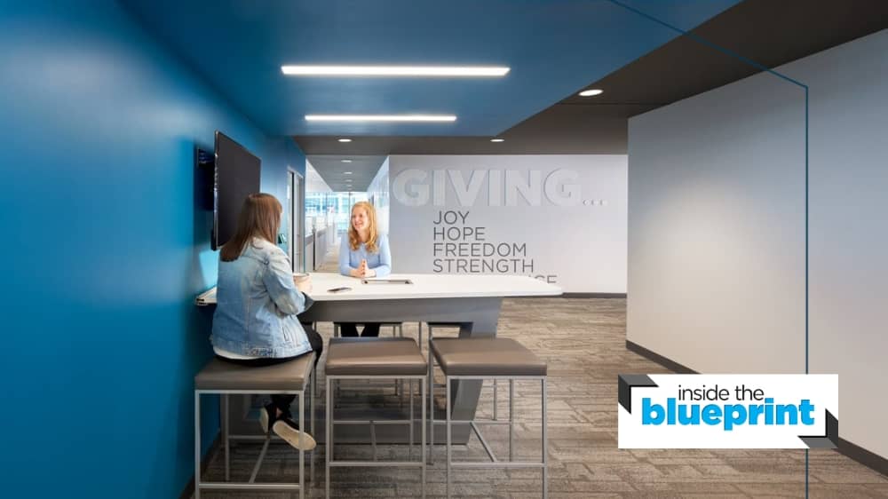 Two office employees sitting at a table and talking.