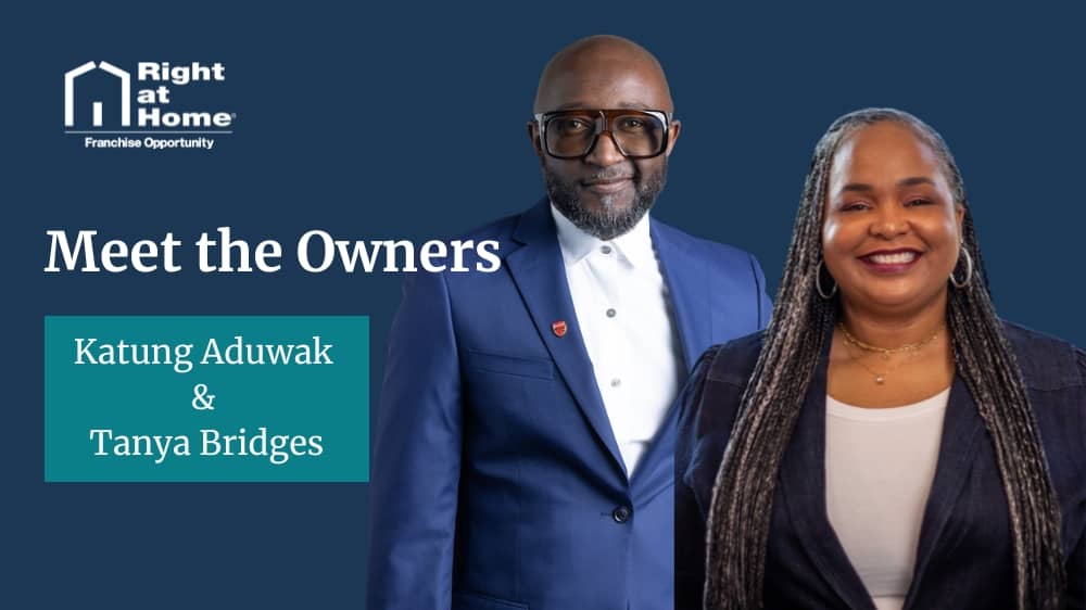 Right at Home franchisees Katung Aduwak and Tanya Bridges standing against a Navy blue background 
