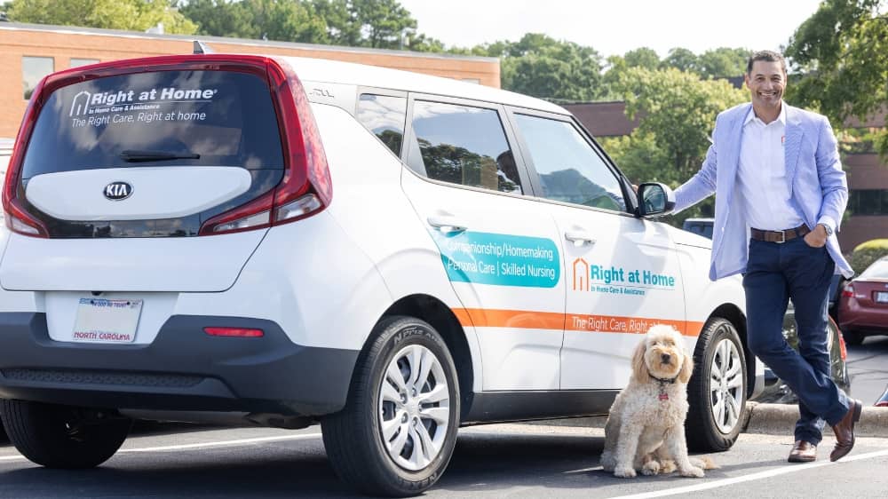 Right at Home franchisee Ken Helmuth standing next to a Right at Home branded care