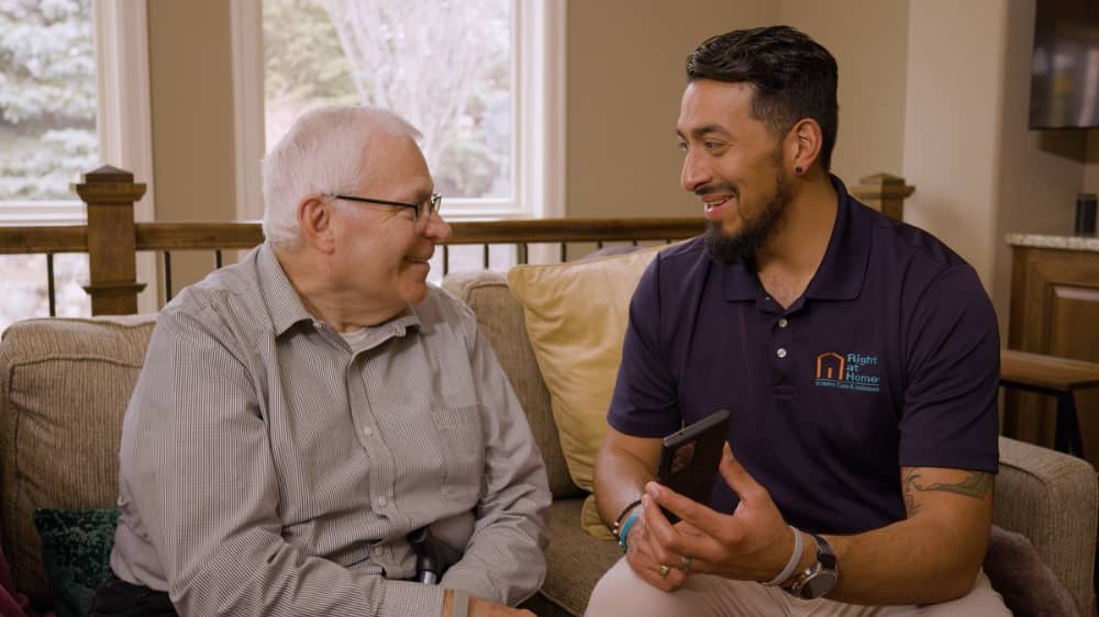 Senior man speaking with a Right at Home owner about RightAssist technology