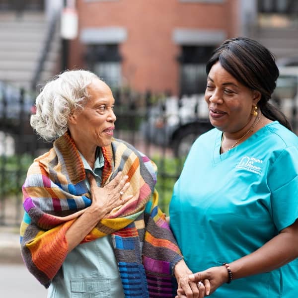 Female Caregiver walking and laughing with a female senior client