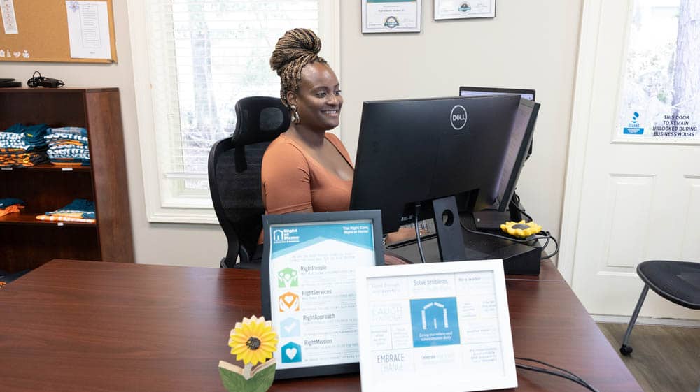A female Right at Home office staff member sitting behind a computer at a desk