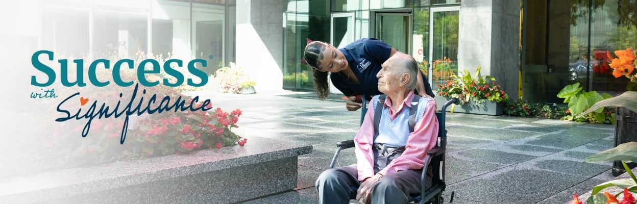 Right at Home Caregiver pushing a wheelchair with her elderly client