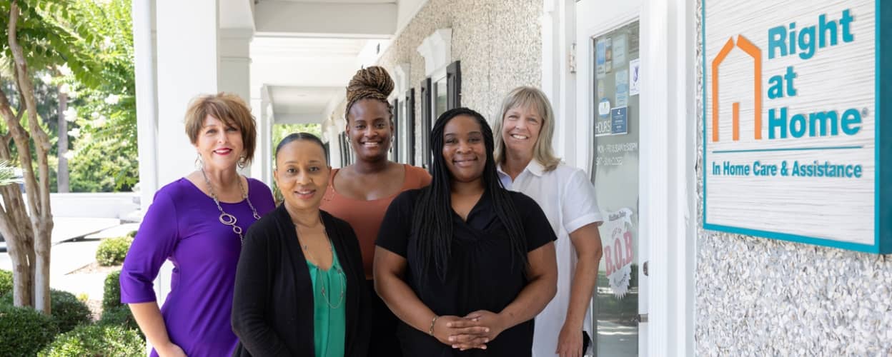 Five women standing outside of a building with a sign that says "Right at Home"