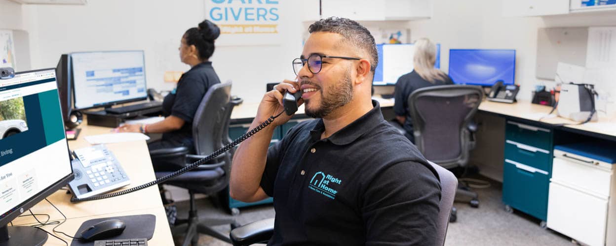 A male Right at Home office staff member is talking on the phone in the office