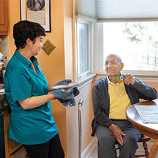 Smiling Right at Home caregiver cooking in the kitchen with a senior male client
