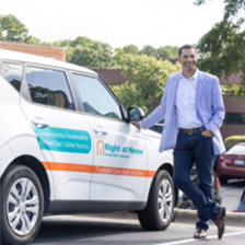 Right at Home franchsiee Ken Helmuth standing next to a company branded car
