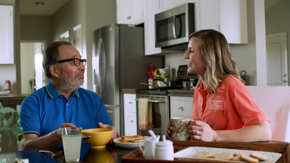 Senior male and female caregiver sitting at the breakfast table
